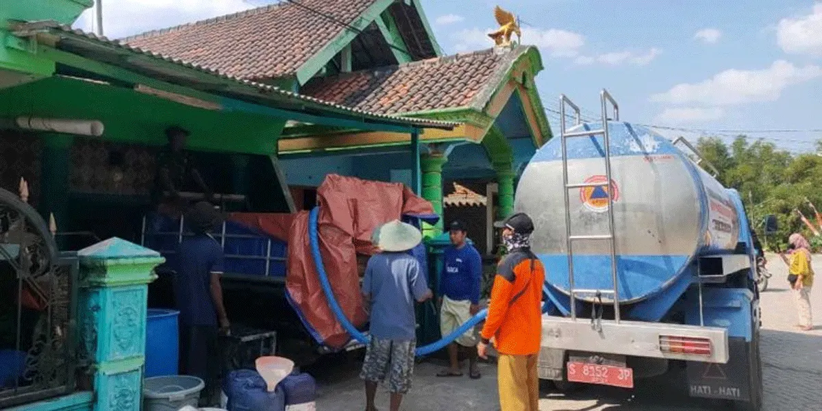 Petugas melakukan distribusi air bersih kepada warga.