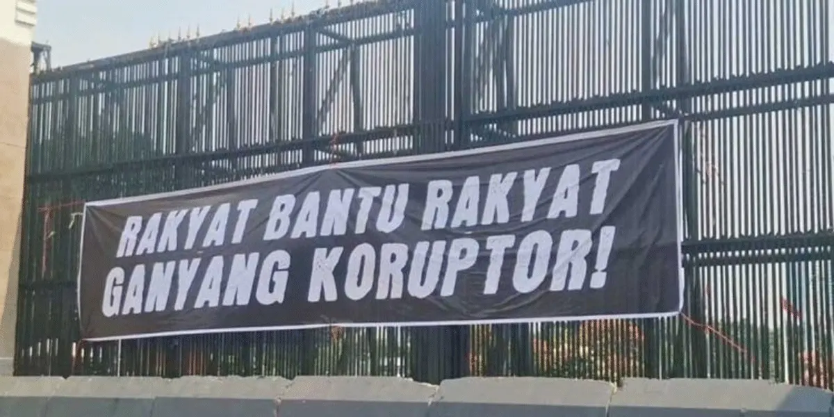 Spanduk bertuliskan kritik tajam kepada koruptor yang dipasang oleh massa aksi dari Pati di pagar gedung DPR, Jalan Gatot Subroto, Jakarta Pusat, Senin (24/8/2026).