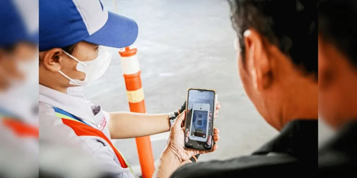 Petugas melakukan proses verifikasi pembayaran digital menggunakan QR Code dalam layanan transportasi.