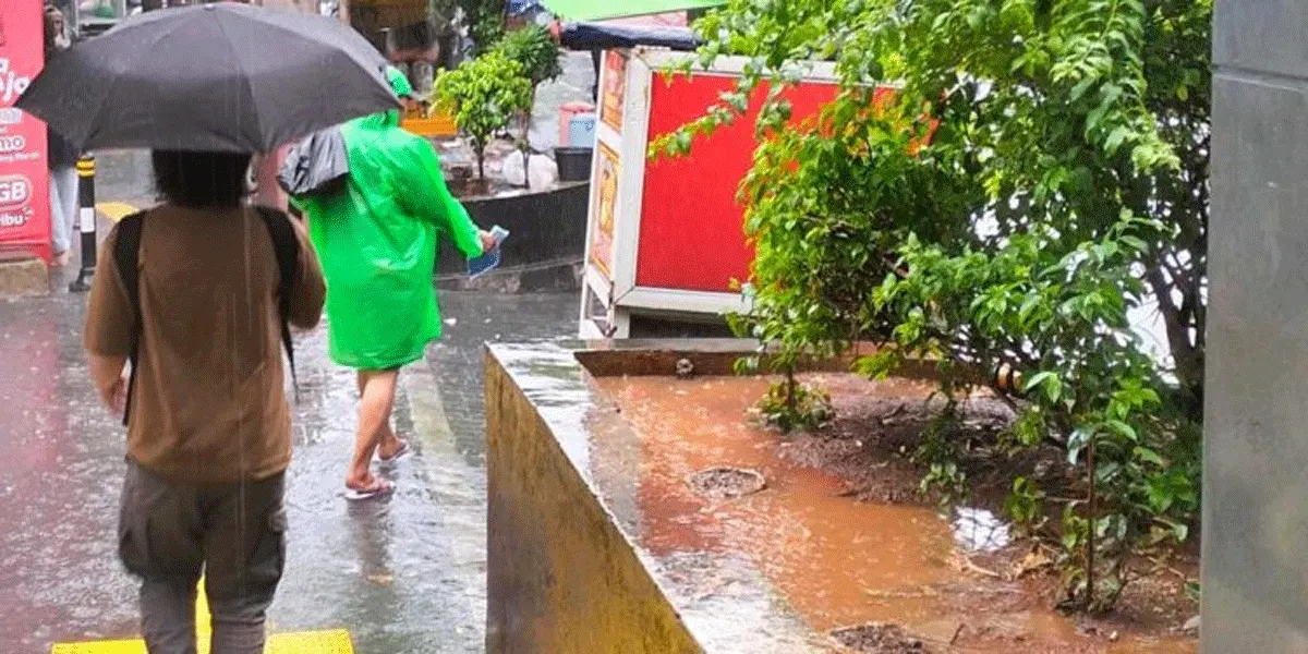 Pejalan kaki menyusuri trotoar saat hujan di Jakarta.