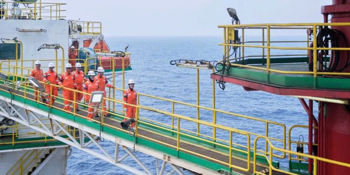 Para pekerja PT Saka Energi Indonesia (SAKA) berjalan di anjungan lepas pantai (offshore platform) dengan mengenakan perlengkapan keselamatan kerja lengkap, mencerminkan komitmen tinggi perusahaan terhadap standar Keselamatan dan Kesehatan Kerja (K3).